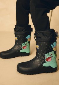 Zwarte rubberen laarzen met Pokémon-personages Bulbasaur en Squirtle, voorzien van een gevoerde zwarte rand en een antislip zool.