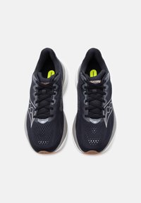 Ζευγάρι μαύρα αθλητικά παπούτσια Saucony με λευκές ενδιάμεσες σόλες και μαύρα κορδόνια, σε άποψη από πάνω σε λευκό φόντο.