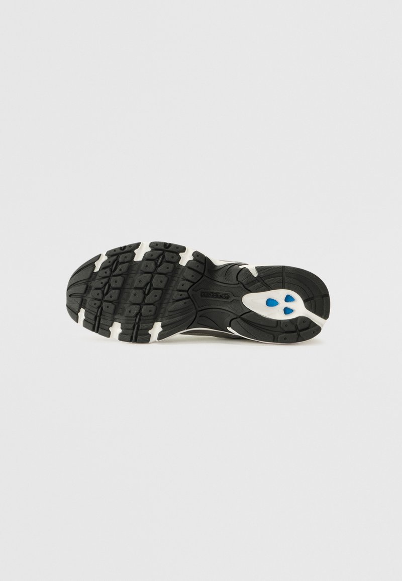 Semelle de chaussure de course noire avec des accents blancs et bleus, présentant un motif texturé pour une meilleure traction et un design courbé pour plus de flexibilité.