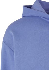 Hanorac albastru deschis cu o textură moale, având un fes cu șnur și un design lejer. Țesătură netedă cu detalii minime de sutură.