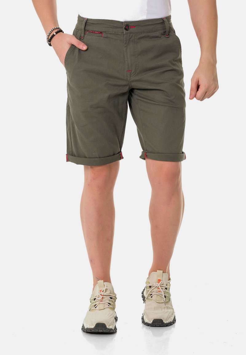 Olijf groene katoenen shorts met opgerolde manchetten, voorzien van contrasterende rode stiksel en een knoopsluiting. Draag je met lichtgekleurde sportschoenen.