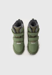 Par de zapatillas verdes para niños con interiores acolchados grises y dos correas ajustables de gancho y bucle sobre un fondo blanco.