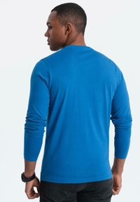 T-shirt azzurro a maniche lunghe in tessuto morbido, con scollatura rotonda e maniche aderenti, mostrato dal retro.