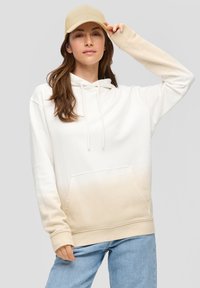 Sudadera con capucha en degradado blanco y beige; tela suave; bolsillo delantero; combinada con una gorra beige; corte relajado; puños y dobladillo acanalados.