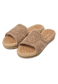 Chanclas marrones con parte superior de tela texturizada que presenta patrones circulares y una plantilla con diseño. La suela tiene un diseño estriado para mayor tracción.