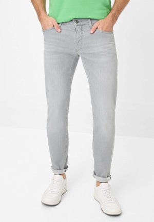 Helle graue Denim-Jeans mit schlanker Passform, ausgestattet mit Fronttaschen, einem Knopfverschluss und umgeschlagenen Säumen, kombiniert mit weißen Turnschuhen.