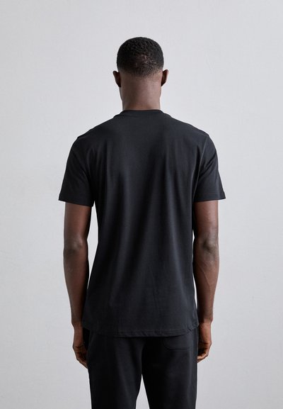 T-shirt noir à manches courtes avec un col rond, fabriqué en tissu lisse. Le dos est uni avec un ourlet légèrement arrondi.