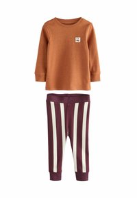 Braunes Langarmshirt mit kleinem Logo-Patch, kombiniert mit lila und weißen gestreiften Leggings. Glatte Stoffqualität und elastischer Bund.