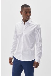Witte langgestreken overhemd met een klassieke kraag, knoopsluiting aan de voorkant en een gladde katoenstof. Gecombineerd met een marineblauwe broek, toont een getailleerde pasvorm.