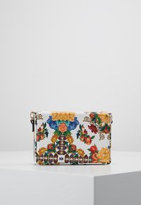 Kabelka přes rameno s květinovým vzorem na bílém pozadí, vyznačující se živými barvami, zlatými akcenty a texturovaným povrchem.