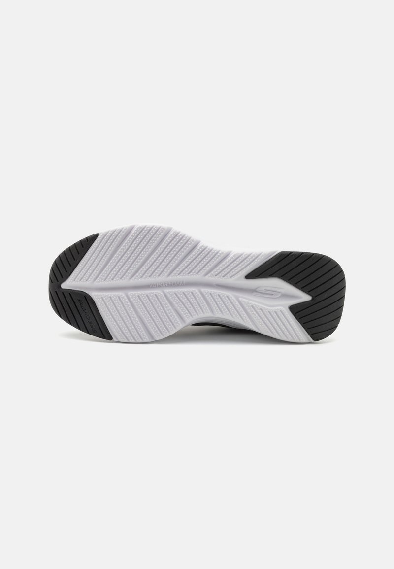 Suela de zapato con una superficie blanca texturizada, con un agarre con patrón y acentos negros en el talón. El material parece flexible y duradero.