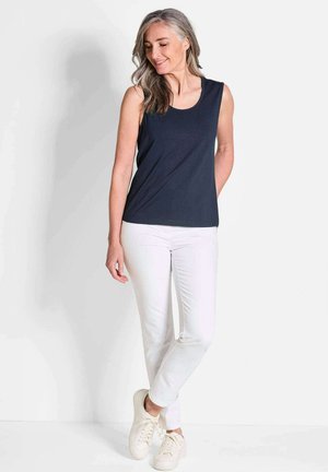Haut sans manches bleu marine associé à un pantalon blanc et des sneakers légères. Le haut présente un col arrondi et une coupe décontractée. Texture de tissu lisse.