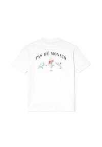 T-shirt bianca a maniche corte con la scritta "PAS DÉ MONACÓ" e illustrazioni floreali colorate sul retro, sopra un piccolo disegno nero a zigzag.