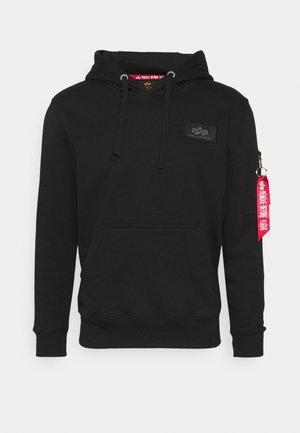 Sudadera negra con capucha hecha de una mezcla de algodón, que presenta un bolsillo frontal, puños elásticos, un parche con el logotipo y un tirador de cremallera rojo.