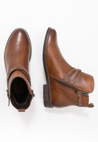 Braune Lederstiefeletten mit einer runden Zehenpartie, seitlichem Reißverschluss und strukturierten Akzentbändern. Mit niedrigem gestapeltem Absatz und kontrastierenden Nähten.