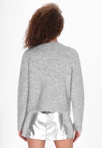 Szary, puszysty sweter dzianinowy z okrągłym dekoltem, opuszczonymi ramionami i luźnym krojem, w zestawie z błyszcząca srebrną spódnicą w kształcie litery A.