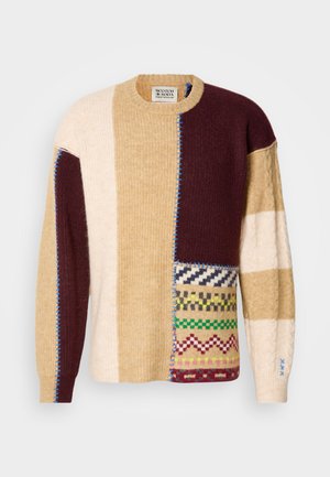 Pulover tricotat cu un design patchwork în bej, burgundy și crem, cu diverse texturi și modele geometrice. Cus�ături albastre contrastante.