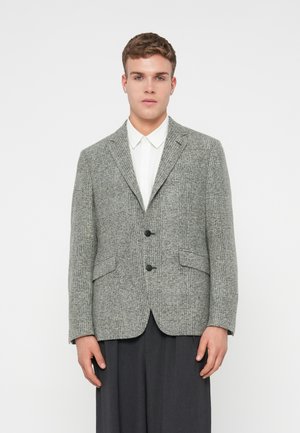 Grau karierter Blazer mit Revers, zwei Vorderseiten-Taschen, Ein-Knopf-Verschluss, strukturierter Webart, getragen über einem weißen Hemd.
