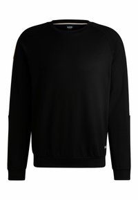 Sweatshirt noir à col rond en tissu doux. Présente des manches raglan, un ourlet côtelé et des accents contrastants blancs et dorés sur les épaules.