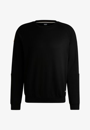 Black crewneck sweatshirt made of soft fabric. Features raglan sleeves, a ribbed hem, and contrasting white and gold accents on the shoulders.