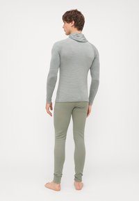 Haut gris à manches longues avec capuche, en tissu texturé et design ajusté, associé à des leggings verts clairs. Construction simpliste et sans couture.