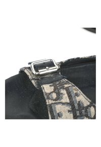 Gros plan d'une bride de chaussure en tissu noir et beige avec une boucle argentée attachée à une semelle de chaussure noire.
