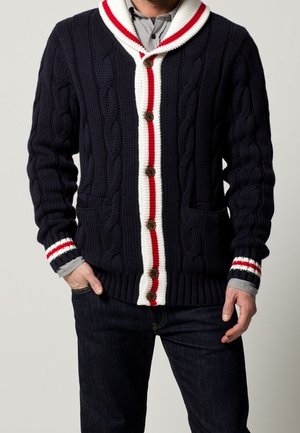 Cardigan lavorato a maglia blu navy con colletto a scialle, dettagli a strisce bianche e rosse, bottoni in legno e due tasche frontali.