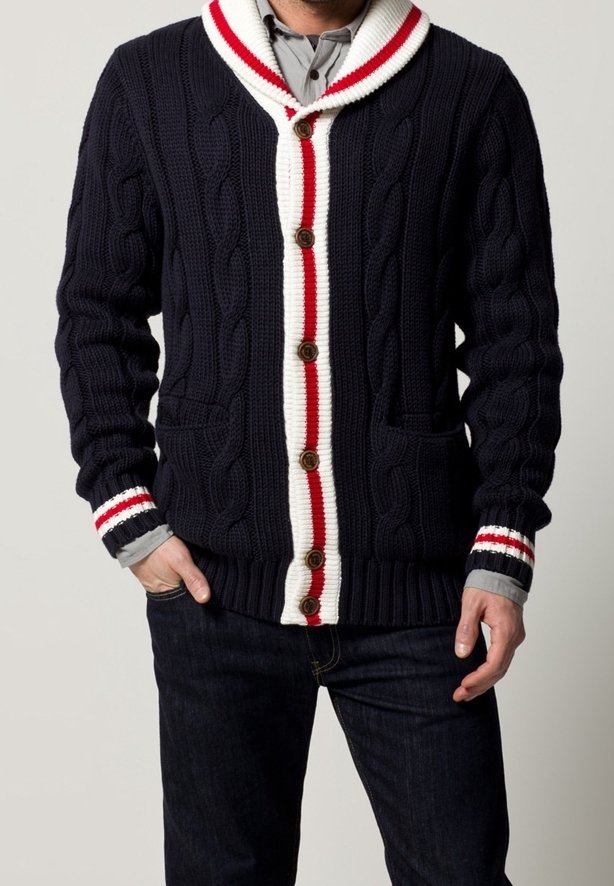 Marinblå kabelstickad cardigan med sjalkrage, vita och röda randiga detaljer, träknappar och två framfickor.