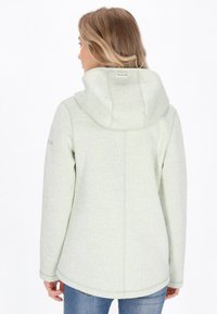 Jasnozielona kurtka z kapturem o teksturowanym wykończeniu, z zaokrąglonym dołem, długimi rękawami i delikatnym wykończeniem szwów na plecach.