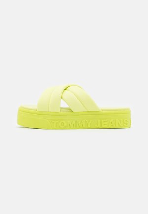 Gul platforms-sandal med polstrede krydsede stofremme og "TOMMY JEANS" prægning på siden af sålen.
