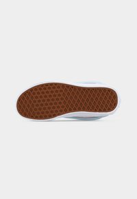 Σόλα παπουτσιού με καφέ λαστιχένιο μοτίβο βουτύρου, λευκό μεσαίο μέρος και ανοιχτό μπλε επάνω μέρος σε απλό γκρι φόντο.