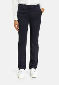 Marinblå skräddarsydda byxor med slät front, mjuk textur, sidofickor och rak skärning, i kombination med vita sneakers.