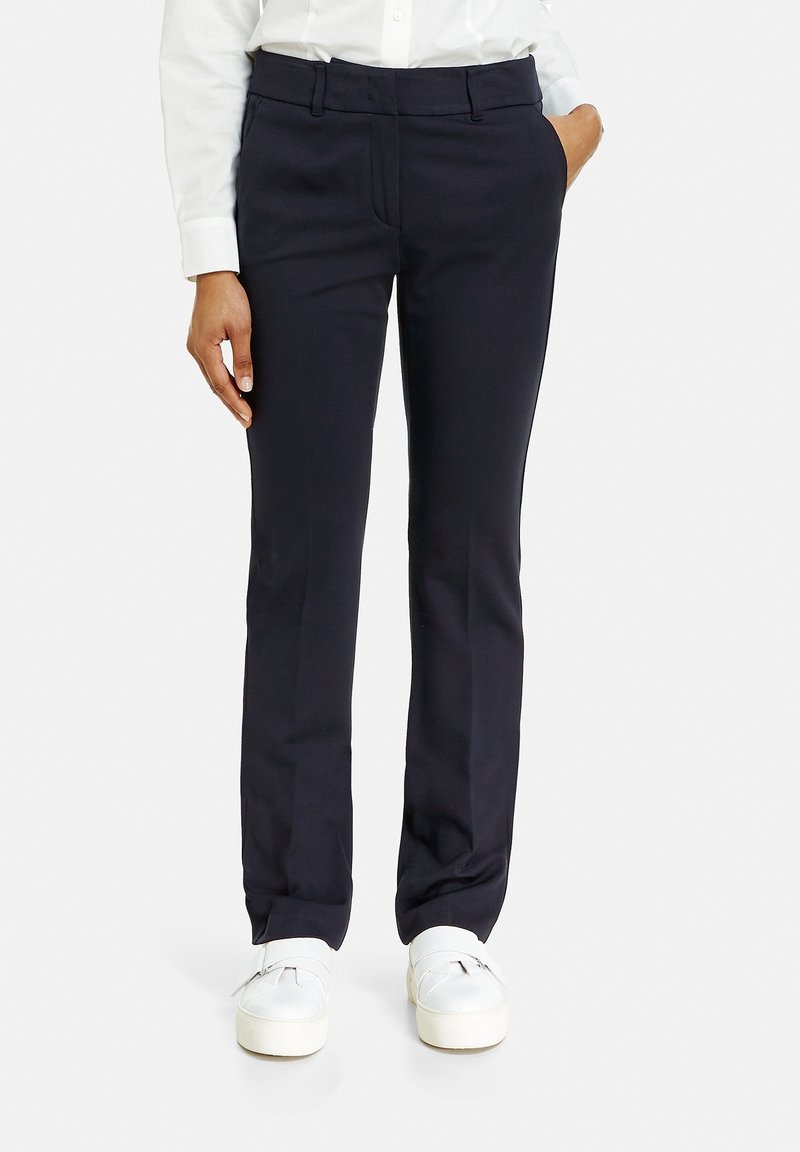 Marinblå skräddarsydda byxor med slät front, mjuk textur, sidofickor och rak skärning, i kombination med vita sneakers.
