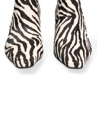 Stivaletti alla caviglia con stampa zebra e punta affusolata, realizzati in pelo testurizzato bianco e nero, caratterizzati da un design elegante e suole nere.