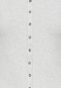 Gros plan sur un tissu gris clair côtelé avec une rangée verticale de petits boutons ronds gris attachés au centre.