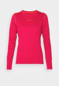 Pitkähihaisen vaaleanpunaisen paidan, jossa on litteät saumat ja pyöreä kaula-aukko. Edessä valkoinen logo ja kontrastina oranssit yksityiskohdat.