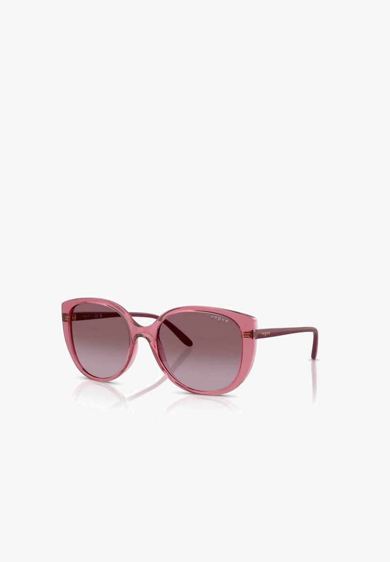 Occhiali da sole rosa traslucidi con lenti sfumate. Forma cat-eye angolare. Stanghette sottili color borgogna con un branding discreto. Dettaglio riflettente in gradiente.