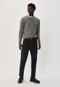 Suéter de punto gris con un cuello redondo, combinado con jeans de mezclilla oscura y zapatos negros tipo slip-on. Diseño simple, textura suave y ajuste casual.