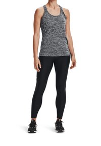 Top sportivo in tessuto grigio melange, abbinato a leggings neri. Le sneakers presentano dettagli in bianco e nero. Design atletico aderente.
