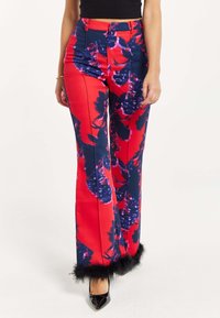 Red floral trousers with navy blue accents, made of a smooth fabric. Features flared legs and black faux fur trim at the hem.