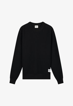 Felpa nera a maniche lunghe con girocollo e polsini a costine, una piccola etichetta bianca vicino all'orlo e un'etichetta del marchio all'interno del colletto.