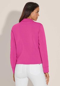 Aansluitende, roze sweatshirt met een kraag en lange mouwen, met een gladde textuur en een cropped design. Gecombineerd met witte jeans.