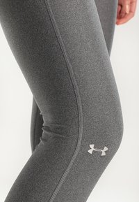 Szare legginsy o gładkiej teksturze, z dopasowanym krojem i subtelnym logo Under Armour w białym kolorze przy łydce.