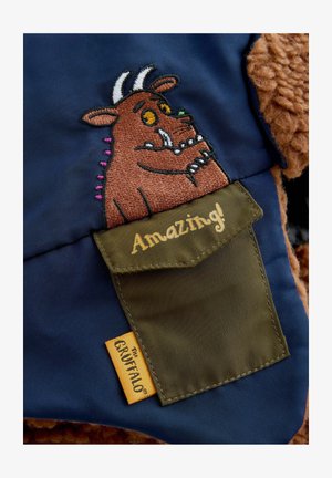 Tengerészkék anyag, amelyen egy hímzett Gruffalo figura látható, barna plüss díszítéssel. A zöld zsebében az "Újra Csodás!" felirat olvasható, és címkét is tartalmaz.