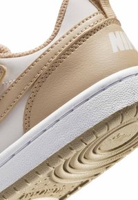 Μπεζ και λευκή σόλα και τακούνι αθλητικού παπουτσιού Nike με υφασμένη εξωτερική σόλα από καουτσούκ και ορατές ραφές στο δερμάτινο πάνω μέρος.