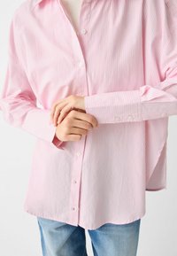 Rosa och vit randig skjorta med knappar, tillverkad av lättviktig tyg, med en klassisk krage och långa ärmar med knäppningar.