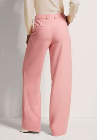 Wijde broekspijpen in zachte roze stof. Hoge taille met achterzakken; soepel textuur en een getailleerde pasvorm bij de taille. Randen zijn netjes afgewerkt.