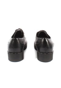 Scarpe in pelle nera con dettagli perforati e tacco basso, caratterizzate da una superficie liscia e una forma arrotondata.