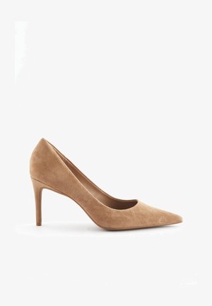 Talons hauts en daim beige avec un bout pointu, un talon fin et une texture lisse. Présente un design classique avec une silhouette épurée.