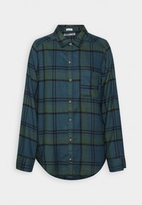 Koszula w kratę z długim rękawem w ciemnozielonym i niebieskim kolorze z czarnymi akcentami, z kołnierzykiem zapinanym na guziki i kieszonką na piersi. Gładka faktura materiału.